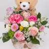 A soft mix of pink and white blooms with a cuddly teddy