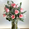 Pink roses in a clear glass vase with white filler flowers