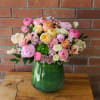 Mixed pastel flower arrangement in a green glass vase
