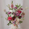 Mixed pink and white flower arrangement in a cream vase with heart decorations
