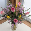 Pink roses and yellow tulips in a clear glass vase with a ribbon