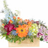 Mixed floral arrangement in a wooden box with orange, blue, and pink blooms
