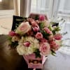 Blush and hot-pink roses and tulips spill from a pink presentation box