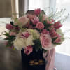 Soft blush roses and bright pink tulips spill from a sleek black