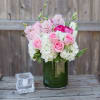 Pink roses and white flowers arranged in a green glass vase