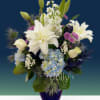 Pale blue hydrangeas and large white lilies create a serene, elegant centerpiece