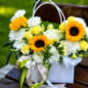 Sunny yellow roses and cheerful sunflowers take center stage in this flower