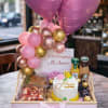 Birthday gift tray with pink heart balloons, cake, and snacks