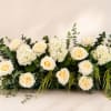 An elevated garden-style centerpiece featuring premium ivory roses, lush white hydrangeas, soft