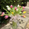 A bouquet of pastel colored tulips arranged in a vase with a