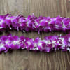 Two purple orchid leis on a wooden surface