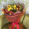 Bouquet of yellow and red tulips wrapped in orange mesh with a pink ribbon