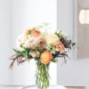 A soft and elegant flower arrangement designed in warm peach, cream, and