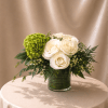 White roses and a green hydrangea in a glass vase