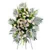 White funeral spray with roses, lilies, and daisies on palm fronds
