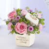 Pink roses and purple flowers in a white vase with a Mother's Day message