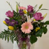 Mixed bouquet of pink, purple, yellow, and white flowers in a glass vase