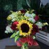Sunflower and red rose bouquet in a glass vase with a red ribbon