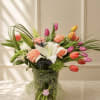 A vibrant arrangement featuring tulips, lilies, garden roses, and fresh greenery in
