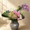 A refined floral arrangement featuring cascading orchids, blush garden roses, hydrangea, lilies