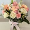 Pink and white flower bouquet in a glass vase with a ribbon