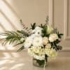 A graceful floral arrangement featuring white chrysanthemums, hydrangea, roses, lilies, and fresh