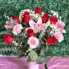 Bouquet of red roses, pink lilies, and carnations in a white vase