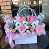 A soft, pastel harvest of nostalgia-this flower arrangement in a white handled