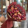 Large bouquet of pink and orange roses wrapped in burgundy paper