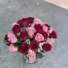 A lush cluster of red and pink roses arranged in a clear