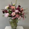 A romantic garden inspired arrangement featuring layers of blush pink, mauve, maroon