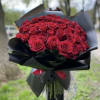 Large bouquet of red roses wrapped in black paper with a red ribbon