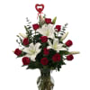 Red roses and white lilies in a clear glass vase with a heart pick