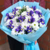 Bouquet of white daisies and purple irises wrapped in blue paper