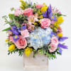 Mixed bouquet in a wooden box with pink roses, blue hydrangea, and purple irises