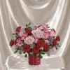 A charming flower arrangement featuring red and blush roses, accented with soft