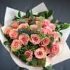 Bouquet of pink roses with white wrapping and greenery