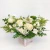 Cream roses and white blooms in a square vase with green accents