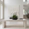 White orchid arrangement in a black bowl on a marble table