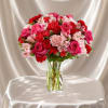 A vibrant flower arrangement featuring hot pink roses, rich red accents, and