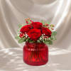 Red roses arranged in a red glass vase