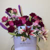 Bouquet of pink roses, lilies, and purple carnations in a gift box