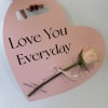 Pink heart-shaped sign with a white rose and the words Love You Everyday