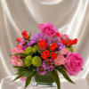 Pink and orange mixed flower arrangement in a square glass vase