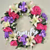 A full-circle silk wreath layered with bright pink peony-style blooms, pale peach