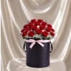 Red roses in a black hatbox with a pink ribbon