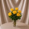 A charming vase filled with  six fresh yellow roses, designed with
