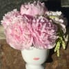 Pink peonies arranged in a white face-shaped vase