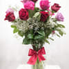 Bouquet of red, pink, and lavender roses in a glass vase with a ribbon