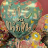 A glossy cluster of heart-shaped foil balloons that says "Love you Mom"